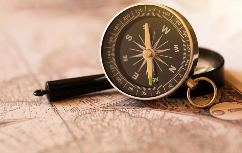 A stylized illustration of a compass sitting on top of a technical blueprint, representing professional intuition