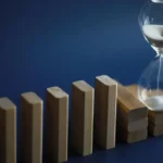 Business English Listening Comprehension - hour glass on dominoes representative of managing timeline shifts