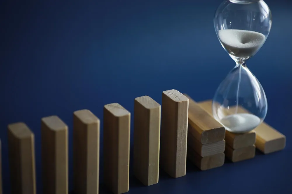 Business English Listening Comprehension - hour glass on dominoes representative of managing timeline shifts