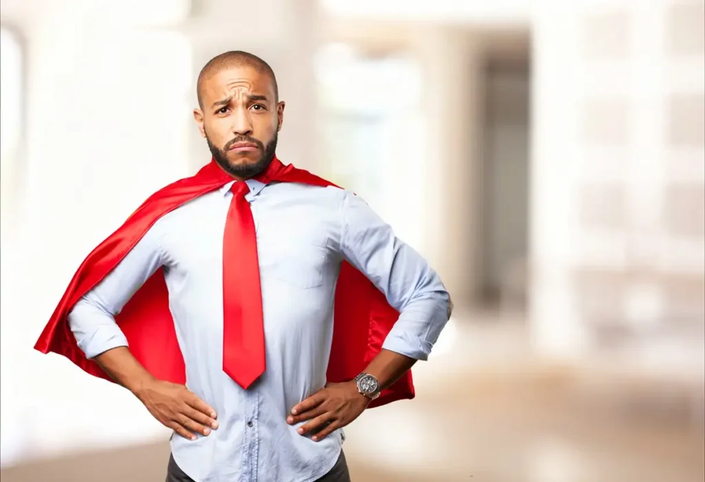 An office professional looks defeated while wearing a red tie and cape, representing someone who is done being a yes-man.