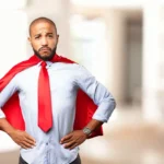 An office professional looks defeated while wearing a red tie and cape, representing someone who is done being a yes-man.