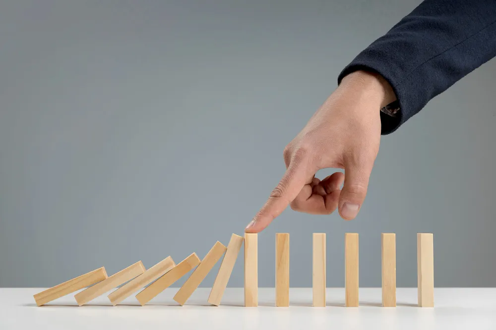 a hand stopping falling dominoes representing professional crisis management